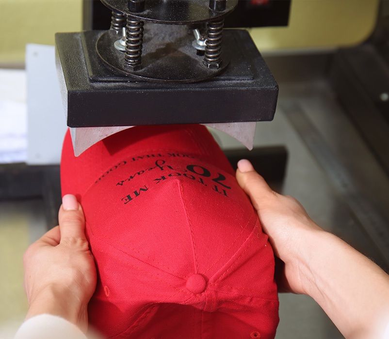 Mitarbeiter beim bedrucken einer roten Kappe