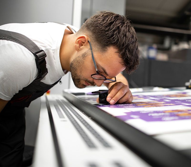 Mitarbeiter bei der Kontrolle der Druckqualität eines gefertigten Produkt